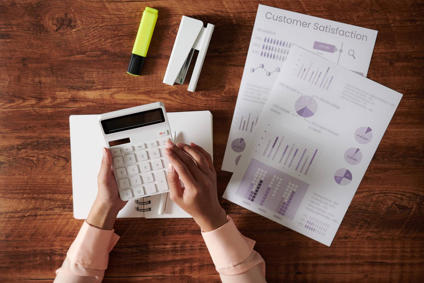 Business manager learning how to measure customer satisfaction of business with papers, pens, and calculator on wooden table