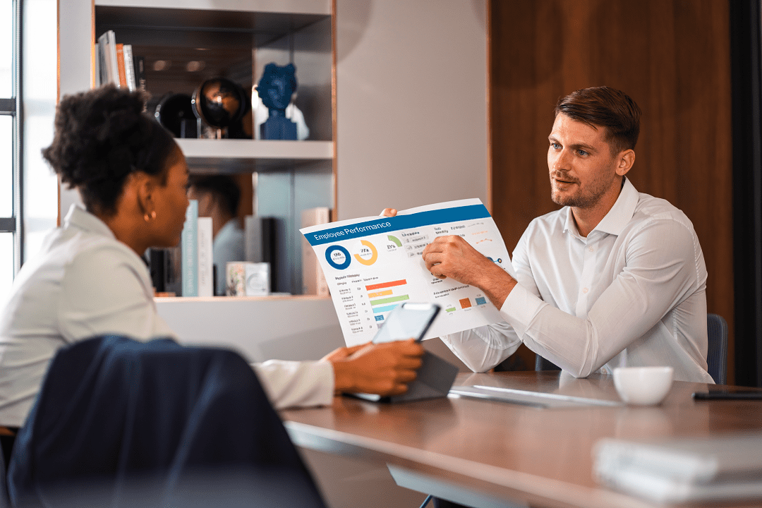 Front desk manager conducting receptionist performance evaluation with receptionist in office