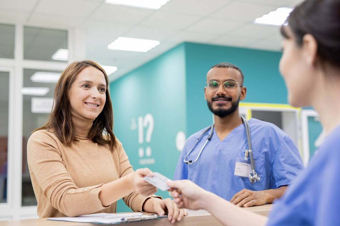 Medical receptionist communicating patient financial responsibility with patient at front desk